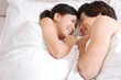 © Blue Jean Images - Asian couple cuddling on bed