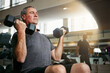 © Grady Reese/peopleimages.com - Fitness, gym and senior man with dumbbells for weightlifting, challenge or cardio workout, training or bodybuilding. Biceps, arms and elderly person with hand weight for strength, mindset or exercise