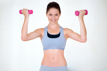 Wall Mural - Woman, strong pose and portrait with dumbbells in studio, wellness and fitness for weight loss with exercise. Young person, flex and face with hand weights for muscle training and white background