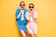 Two young beautiful smiling brunette hipster female in trendy summer clothes. Sexy carefree women near yellow wall in studio. Positive models having fun. Cheerful and happy. Shocked and surprised