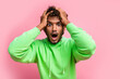 Portrait of speechless funny young indian guy green sweatshirt confused hands touch head shocked staring isolated on pink color background