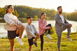 © Studio Romantic - Fit and active happy parents with two kids boy and girl doing sport exercises in nature. Smiling family in sportswear having workout in the park. Outdoors training and fitness concept.