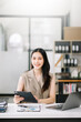 © Nuttapong punna - Asian Businesswoman Analyzing Finance on Tablet and Laptop at modern Office Desk tax, report,
