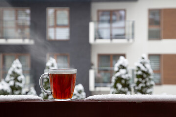 Wall Mural - glass cup of tea in snow on balcony in winter