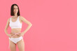 A slim girl in underwear measures her waist.