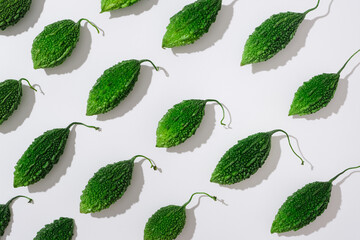 Sticker - Fresh green bitter melons arranged on a white background. Creative scene for advertising and branding for cosmetic or product with ingredient from bitter melon (Momordica charantia)