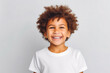 Cute mixed race boy child model with perfect clean teeth laughing and smiling, happy. Curly hair and white shirt, healthy. Isolated on white background.