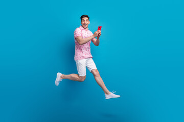 Poster - Full size profile portrait of astonished person jump use smart phone empty space isolated on blue color background