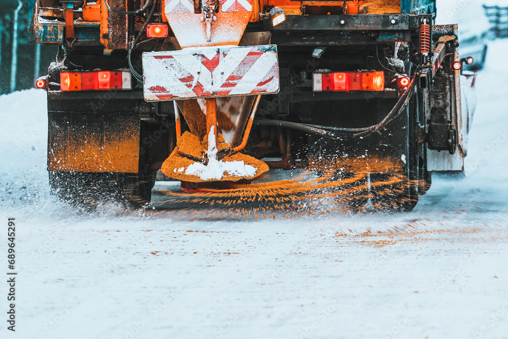 A snowplow truck applies salt and sand as the truck works to clean the ...