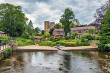 The River Skell In Ripon, With The Cathedral Standing Majestically Beyond, In The Borough Of Harrogate, North Yorkshire.