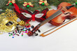 Violin with bow, carnival masks and Christmas decorations.