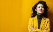 Thoughtful Asian businesswoman in a yellow turtleneck and blazer standing with crossed arms against a matching yellow background, exuding confidence and professionalism
