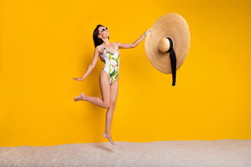 Poster - Full length photo of cheerful positive lady wear swimsuit jumping high rising sun headwear empty space isolated yellow color background