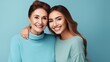 © ckybe - Smiling happy pleasant content senior mother with grown-up child daughter two ladies embracing embrace gaze at lens isolated on simple aqua blue background. Parent-child bonding idea.