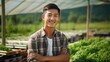 Asian young man wearing plaid shirt smiling at vegetable farm. Farmer man concept.