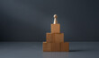 © robert - concept of being a winner ,wooden figure standing ontop of blocks , with a grey blue background . success in business ,