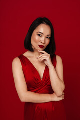 Wall Mural - Lovely asian woman posing isolated over red background