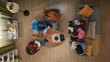 © kinomaster - Top view of a group of female students sitting in a living room studying for an exam. Young women are using laptop, tablet, reading books and taking notes.
