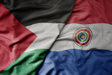 big waving national colorful flag of paraguay and national flag of palestine .