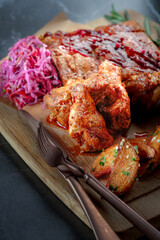 Wall Mural - Barbecue wings and ribs on a wooden board with grilled potatoes and sauerkraut. Meat appetizer for beer