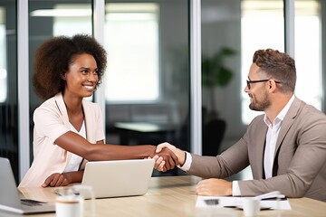 Wall Mural - Happy professional mature businessman and businesswoman wearing suits shake hands sitting at table having partnership business contract agreement with handshake at corporate meeting in office.