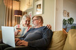 © Marko Geber - Happy senior couple paying with credit card on laptop at home