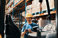 Smiling young man using smartphone in warehouse