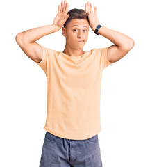 Wall Mural - Young handsome man wearing casual clothes doing bunny ears gesture with hands palms looking cynical and skeptical. easter rabbit concept.