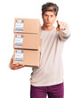 © Krakenimages.com - Young handsome man holding delivery package pointing with finger to the camera and to you, confident gesture looking serious