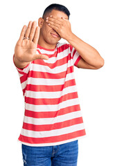 Wall Mural - Young handsome latin man wearing casual clothes covering eyes with hands and doing stop gesture with sad and fear expression. embarrassed and negative concept.