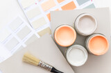 Fototapeta Tulipany - Tiny sample paint cans during house renovation, process of choosing paint for the walls, Peach Fuzz color of the year 2024, color charts on background