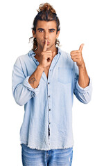 Wall Mural - Young hispanic man wearing summer style asking to be quiet with finger on lips pointing with hand to the side. silence and secret concept.