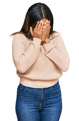 Canvas Print - Young latin girl wearing wool winter sweater with sad expression covering face with hands while crying. depression concept.