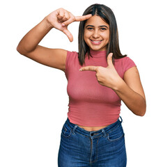 Poster - Young hispanic girl wearing casual t shirt smiling making frame with hands and fingers with happy face. creativity and photography concept.