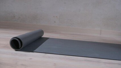 Wall Mural - A man rolls a yoga mat in the studio, close-up.