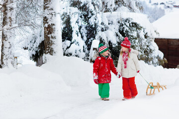 Wall Mural - Kids play in snow. Winter sleigh ride for children