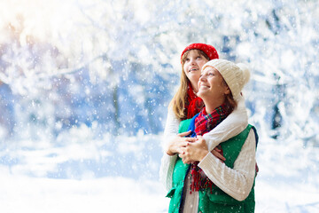 Wall Mural - Mother and child in knitted winter hats in snow.