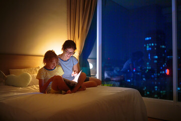 Wall Mural - Child and mother read a book in dark room.