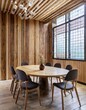 © Martin - Round wooden slab dining table and chairs around it against barn wood board paneling wall. Japandi interior design of modern dining room.