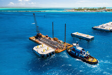 Aerial View Of Pier Construction In The Bahamas. The Tug Boat, Miss Ashley, Supports A Barge And Crane Alongside The Pier, Berry Islands, The Bahamas.