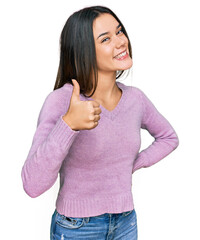 Wall Mural - Young hispanic girl wearing casual clothes doing happy thumbs up gesture with hand. approving expression looking at the camera showing success.