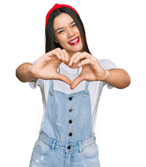 Canvas Print - Young hispanic girl wearing casual clothes smiling in love doing heart symbol shape with hands. romantic concept.