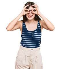 Wall Mural - Young beautiful caucasian girl wearing casual clothes and glasses doing ok gesture like binoculars sticking tongue out, eyes looking through fingers. crazy expression.