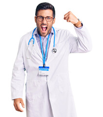 Wall Mural - Young hispanic man wearing doctor uniform and stethoscope angry and mad raising fist frustrated and furious while shouting with anger. rage and aggressive concept.