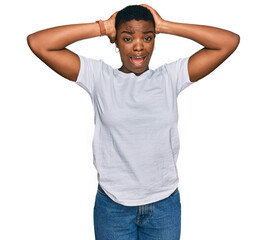 Canvas Print - Young african american woman wearing casual white t shirt crazy and scared with hands on head, afraid and surprised of shock with open mouth