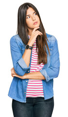 Wall Mural - Young brunette woman wearing casual clothes with hand on chin thinking about question, pensive expression. smiling with thoughtful face. doubt concept.