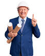 © Krakenimages.com - Senior handsome grey-haired man wearing architect hardhat holding blueprints surprised with an idea or question pointing finger with happy face, number one