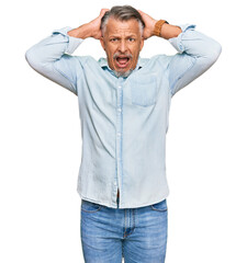 Poster - Middle age grey-haired man wearing casual clothes crazy and scared with hands on head, afraid and surprised of shock with open mouth