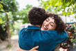 © Brastock Images - Young woman smiling, hugging her girlfriend on date in the park.