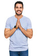 © Krakenimages.com - Young hispanic man wearing casual clothes praying with hands together asking for forgiveness smiling confident.